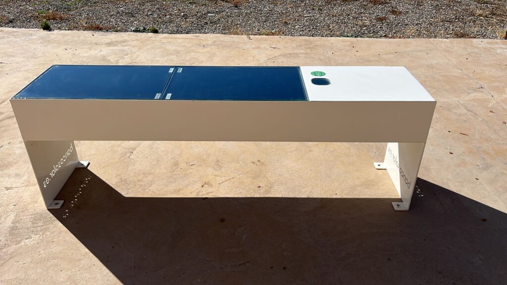 Los bancos solares con carga para móviles convierten el mobiliario urbano en un punto de descanso y energía para los usuarios. En Banco Solar Inteligente fabricamos en España bancos solares diseñados para espacios exteriores que aprovechan la energía solar y permiten incorporar sistemas de carga USB y carga inalámbrica para dispositivos compatibles. Una solución pensada para ayuntamientos, parques, hoteles, universidades, centros comerciales, puertos y proyectos Smart City. ¿Cómo funciona un banco solar con carga para móviles? El banco incorpora un sistema fotovoltaico que capta la energía solar y la utiliza para alimentar las diferentes funcionalidades instaladas. De esta forma, los usuarios pueden sentarse y cargar su teléfono móvil directamente desde el banco solar, sin necesidad de buscar un enchufe convencional. Dependiendo de la configuración seleccionada, nuestros bancos pueden incorporar: - Puertos de carga USB. - Carga inalámbrica para dispositivos compatibles. - Iluminación LED nocturna. - Conectividad WiFi 4G opcional. - Sensores ambientales. - Espacios para publicidad y personalización. Carga USB integrada Los puertos USB permiten conectar directamente dispositivos compatibles mientras el usuario permanece sentado en el banco.